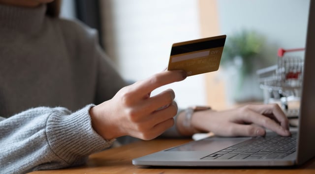 A Woman Holding A Credit Card And Using A Laptop
